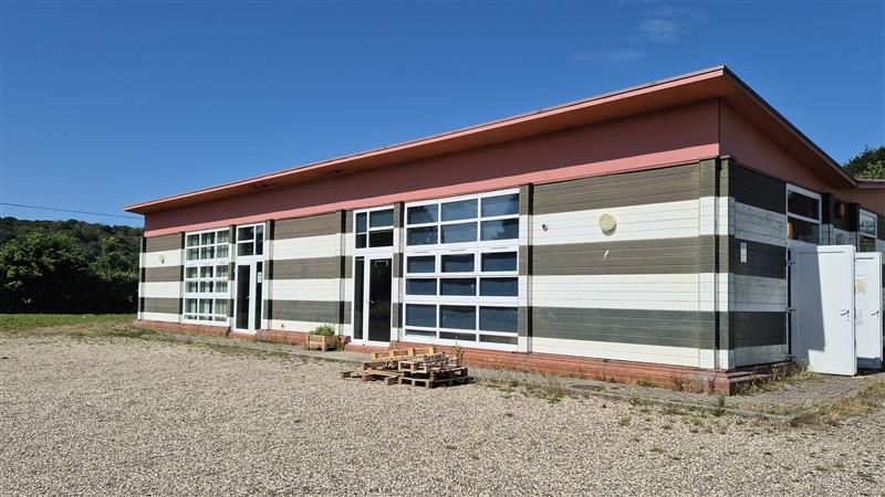 The attendance hub at Astor School is a striped building in a separate part of the school grounds surrounded by shingle