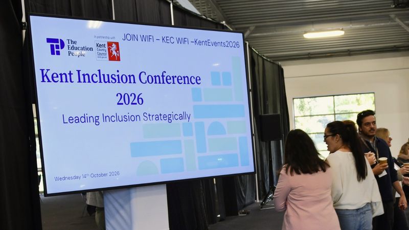 A screen says Kent Inclusion Conference as people walk by