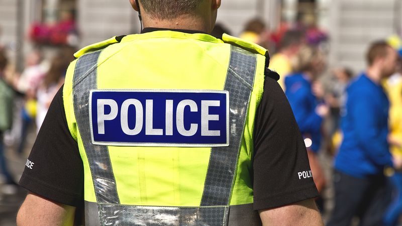 The back of a Policeman showing a high vis uniform showing "POLICE"