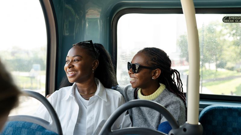 Two women laugh together on the bus