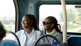 Two women laugh together on the bus