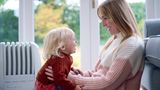 smiling mum and toddler wearing jumpers in front of radiator