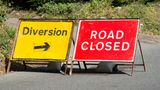 Two road signs on a road. The one on the left is a red rectangle with the words 'road closed' in the centre. The other sign is a yellow rectangle with the words 'diversion'.