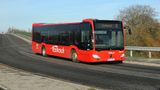 A red bus drives down a road. The bus says 'Gravesend B' on the front at the top.