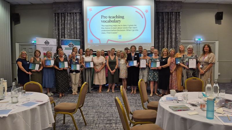 A group photo of teachers smiling and holding their Scheme for Schools and Settings accreditation certificates