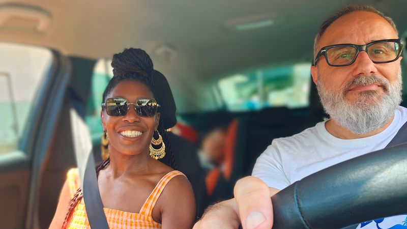 Guilio at the steering wheel with Tracy in the front passenger seat beside him.  