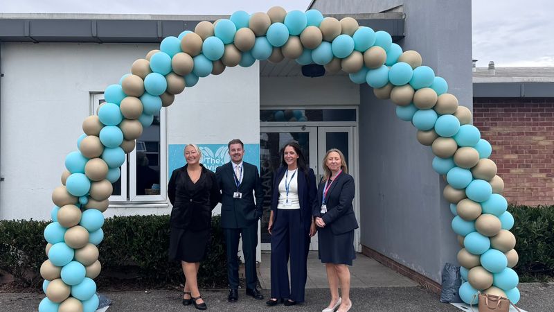 4 people standing in front of a balloon arch