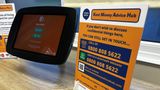 Kent Money Advice Hub poster displayed on countertop with tablet. It says "if you don't wish to discuss confidential things here. You can still get in touch, call 0800 808 5622 whatsapp the same number or visit www.kentmoneyadvicehub.com. Speak with our advisors straight away or ask for a video call back