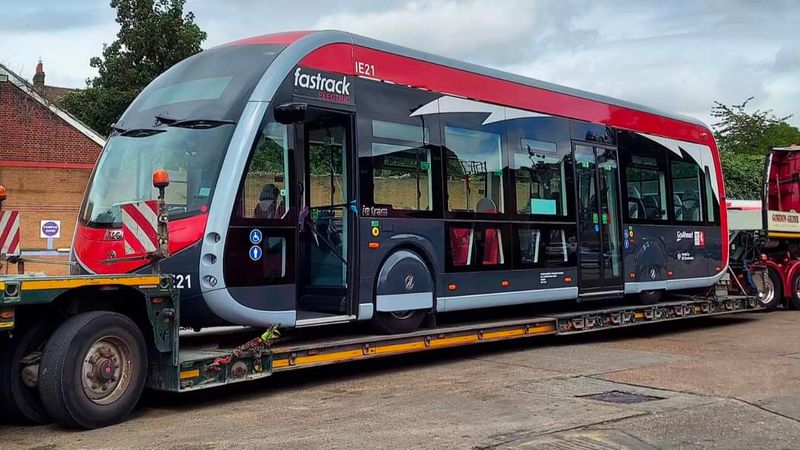 A photograph of a new Fastrack electric bus being delivered on a lorry.