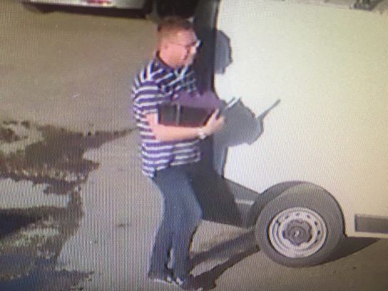 A man walks past a van with a laptop in his hand. It is a still taken from CCTV