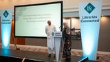 Sue Carmichael standing on a stage giving a speech as she collects her Libraries Connected award.