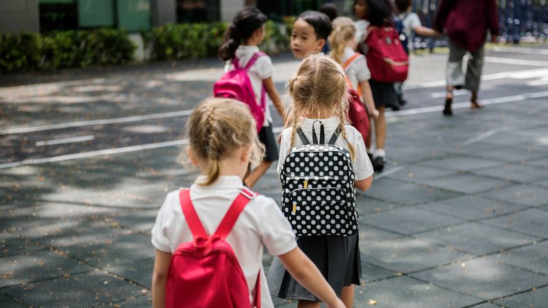 School children walking into school with backpacks on