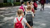 School children walking into school with backpacks on