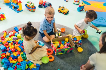 Two toddlers playing with colourful building blocks.