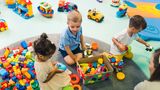 Two toddlers playing with colourful building blocks.