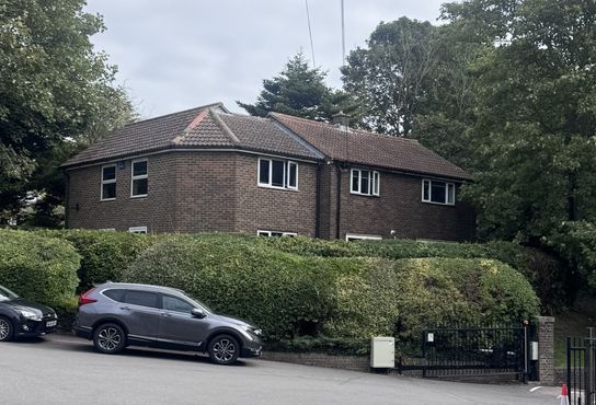 a large brown bricked building with bushes and cars in front of it