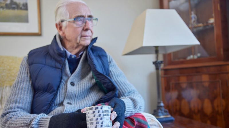Elderly man keeping warm with hot drink and blanket