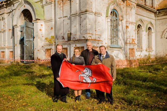 The Kent flag is held in front of a war-torn building in Ukraine by KCC's Roger Gough and Jordan Meade 