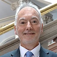 Chris Hespe is smiling for his headshot photo in front of the county hall steps