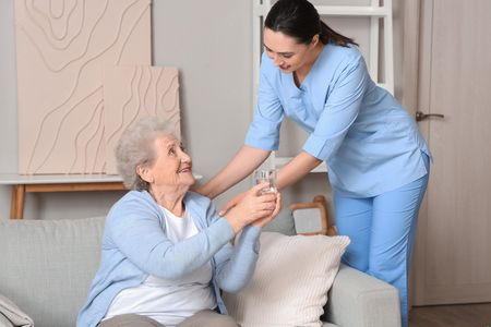 Woman in care home shares water with her carer 
