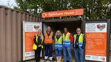 Five people wearing high-viz jackets standing outside a container that is labelled "furniture reuse" at Maidstone HWRC