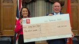 Leader and Deputy Leader of KCC hold a large cheque that represents a debt repayment