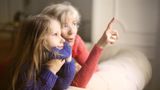 A young girl with her grandmother wearing jumpers and looking out the window
