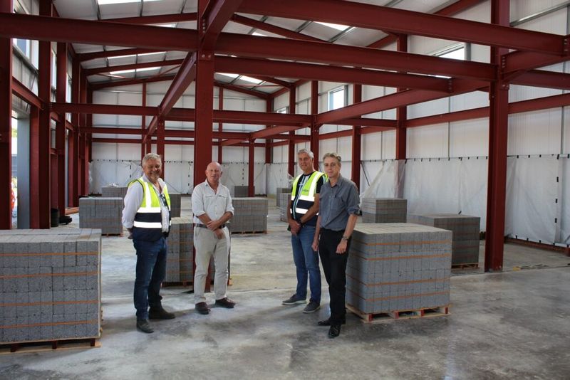 Staff standing inside the new no use empty warehouse with pallets around them