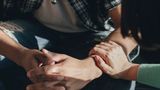 A woman reassures a man by placing her hand on his arm