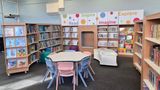 The colourful new children's section at Temple Hill Library has a book nook to sit in, a table and chairs in the middle and is surrounded by bookshelves. The words read, inspire, imagine and explore are written on the shelves 