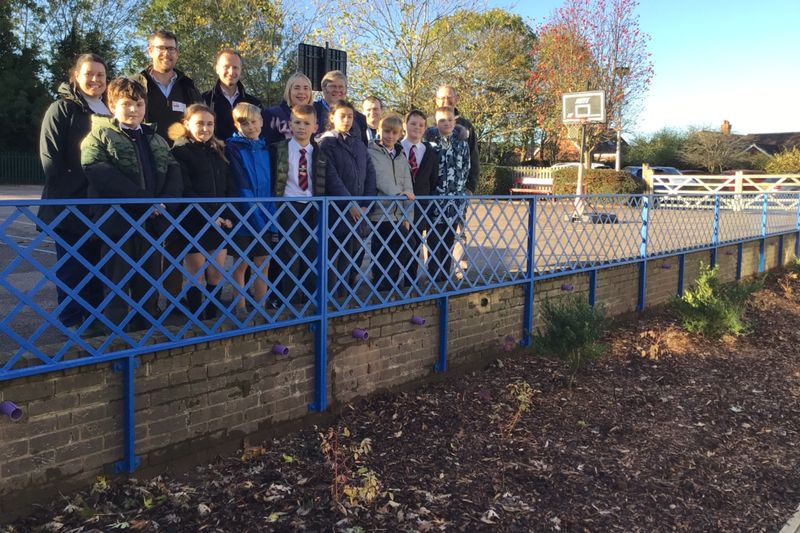 Project members and school children standing on the walkway next to the rain garden at St Katherine's school