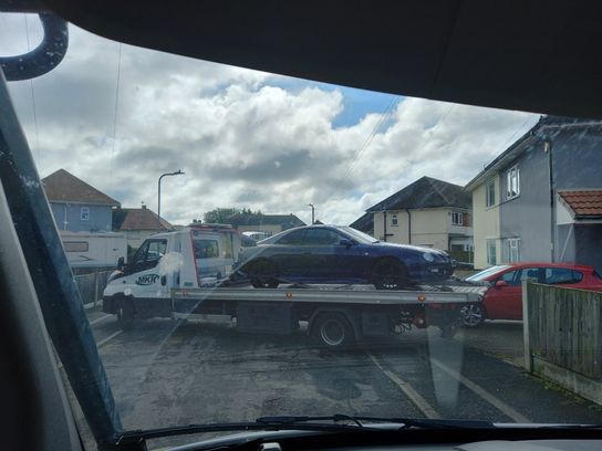 Car on a flatbed lorry being seized as part of an operation