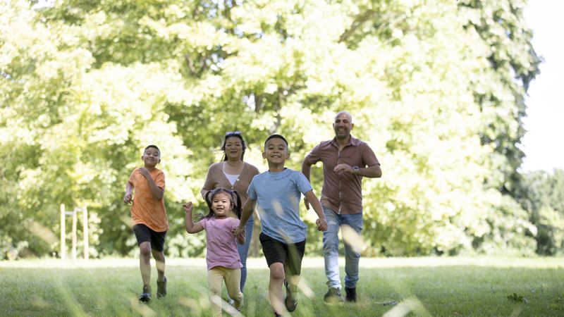 Family energetically walking across a park in sunlight
