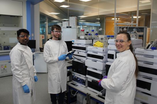A group of three scientists amongst science instruments and technology in the lab