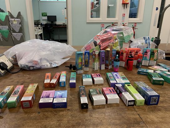 Brightly coloured and packaged vape products lined up on a table