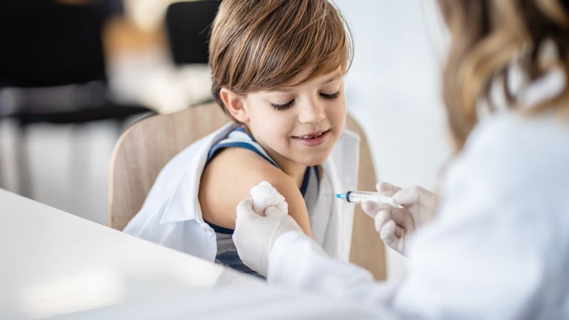 Young boy looks at his arm as a nurse prepares to give him a vaccination