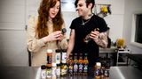 A couple look at bottles and jars of condiments in a commercial kitchen setting