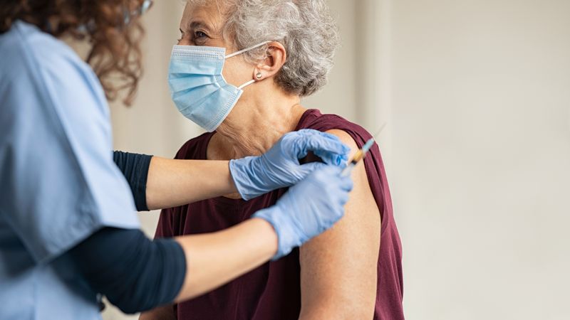 Elderly woman being vaccinated by doctor
