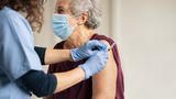 Elderly woman being vaccinated by doctor