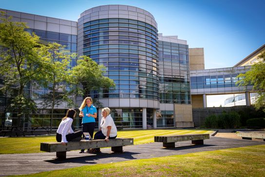 A view of Discovery Park with three people gathered together around a bench in the foreground