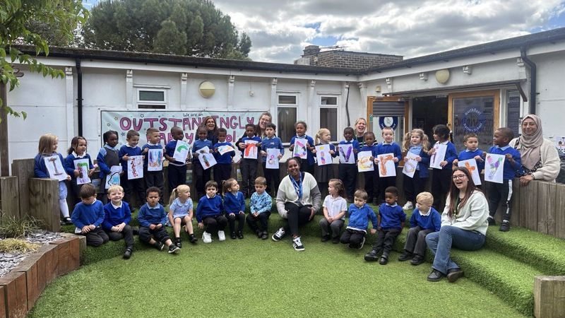Pupils at Northfleet Nursery stand in a line in the school playground holing up colourful letters spelling 'inclusion and diversity' with the help of teachers