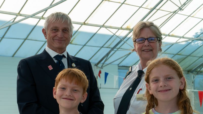 Two smiling children with two smartly dressed adults behind them at an indoor swimming pool 