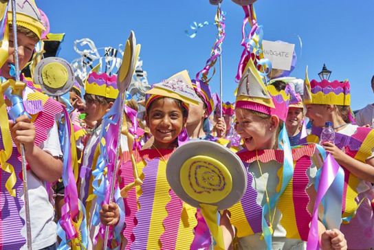 Smiling children in bright pink, yellow and lilac homemade costumes