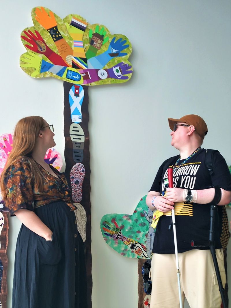 Professional artist Hannah Whittaker and collaborator Nim Thorpe standing in front of the colourful 'Draw Hope' trees  