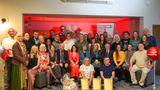 Foster Carer award winners on red backlit stage with red, white and silver balloons and 'Foster for Kent' poster