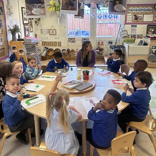 Pupils from Northfleet Nursery sat at a round table with their teacher decorating colourful letters