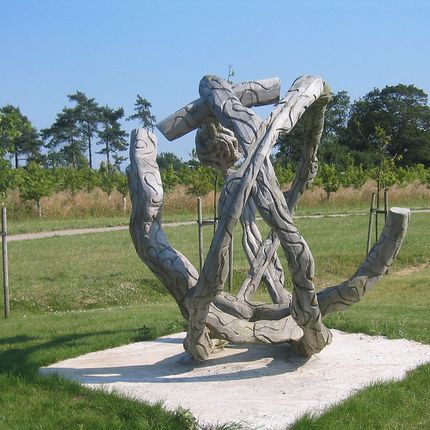 Outdoor sculpture made of intertwined, curved stone-like structures on a grassy field.