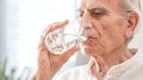 Elderly man drinks a glass of water