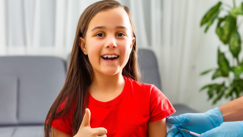 Young girl gives thumbs up as she has a vaccination