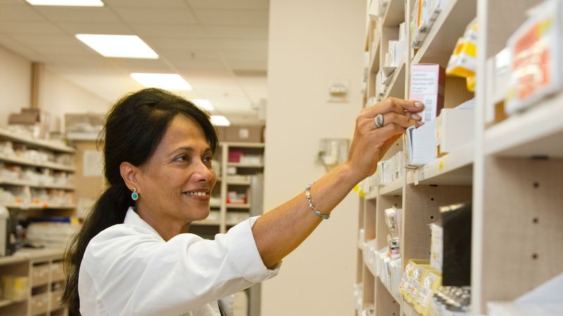 Woman pharmacist puts medicine on shelf